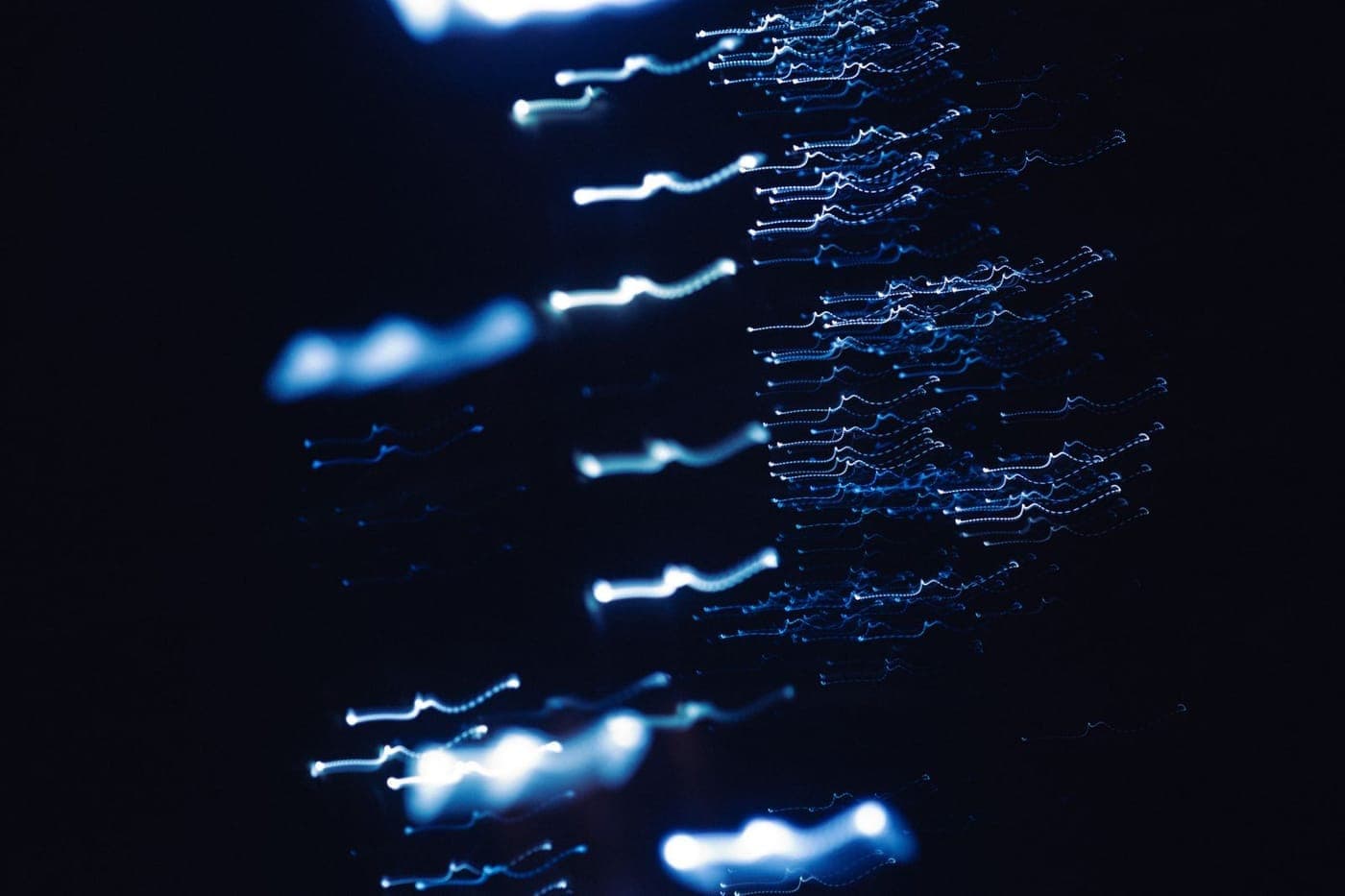 Abstract blue light dots and streaks flowing across a dark background, like a trace of events