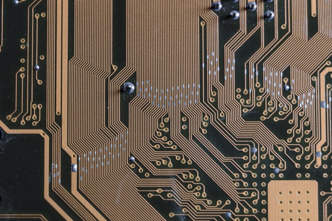 Macro of gold circuit-board traces on a dark green printed circuit board