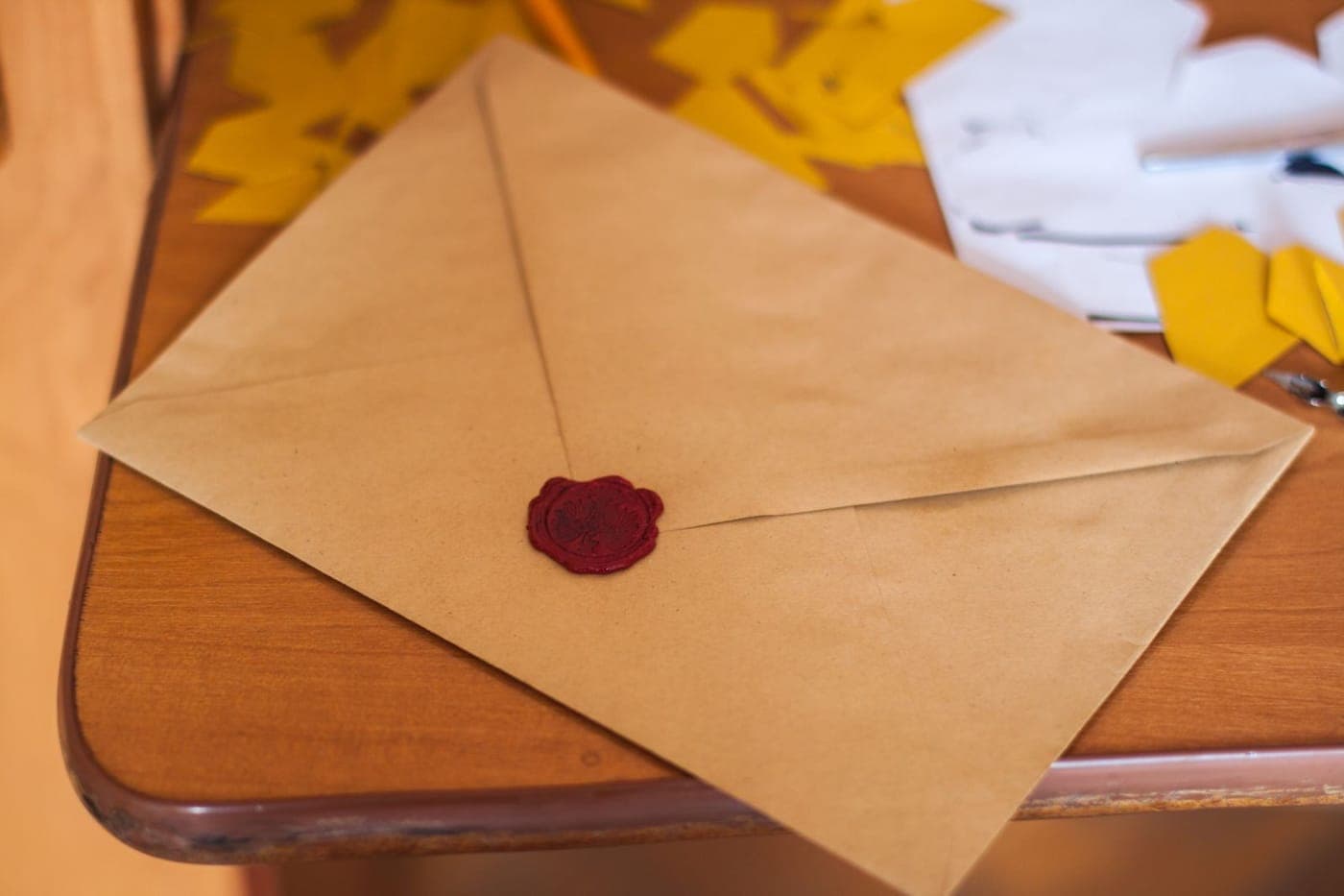 Kraft-paper envelope sealed with red wax resting on a warm wooden table