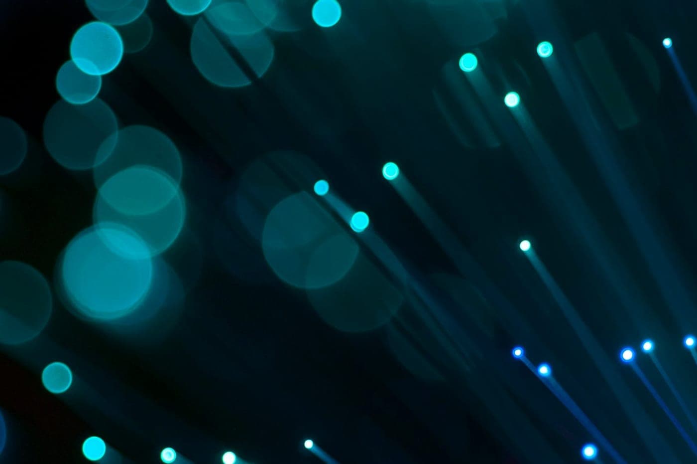 Glowing blue and teal fiber-optic strand tips with soft bokeh on a dark background