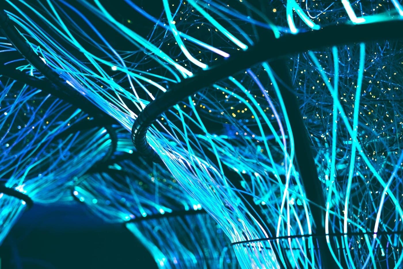 Glowing blue fiber-optic strands forming a dense connected network on a dark background