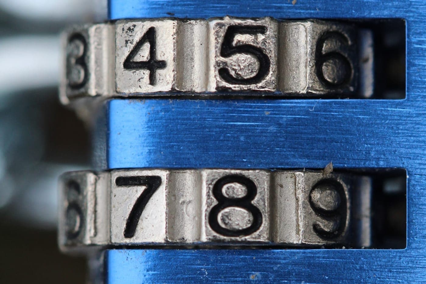 Macro of a combination padlock's numbered dials on blue metal
