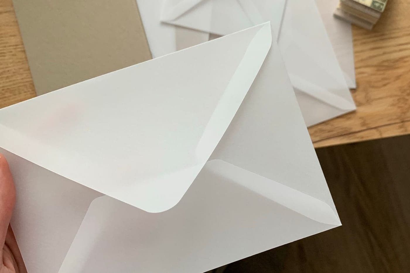 White envelope held over a warm wooden table