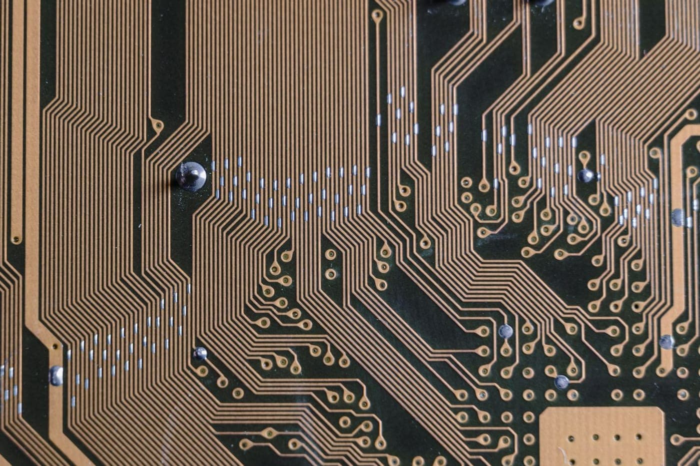 Macro of a circuit board with intricate gold traces on dark green