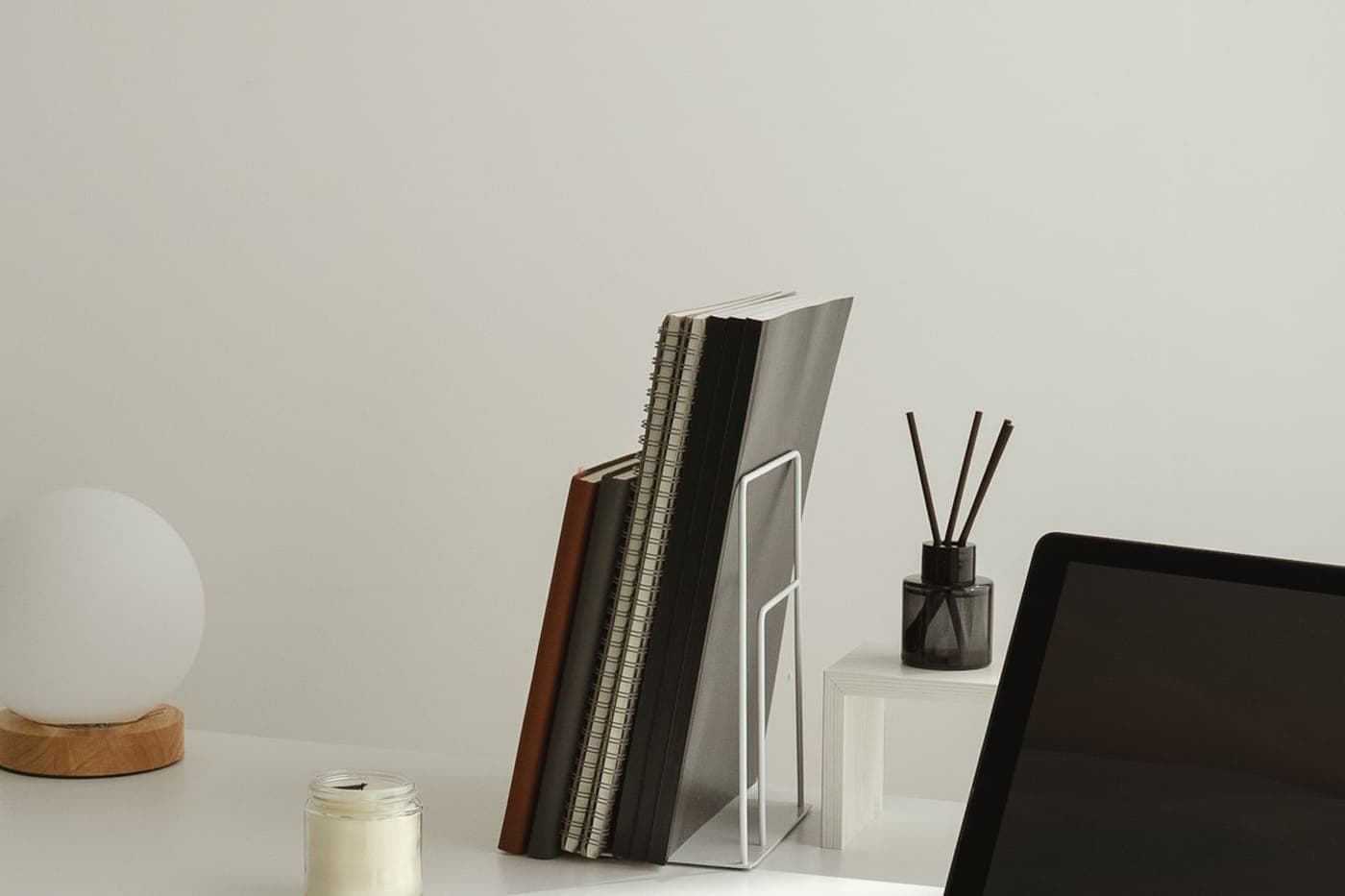Calm minimal desk with notebooks, a globe lamp and a laptop in soft neutral tones