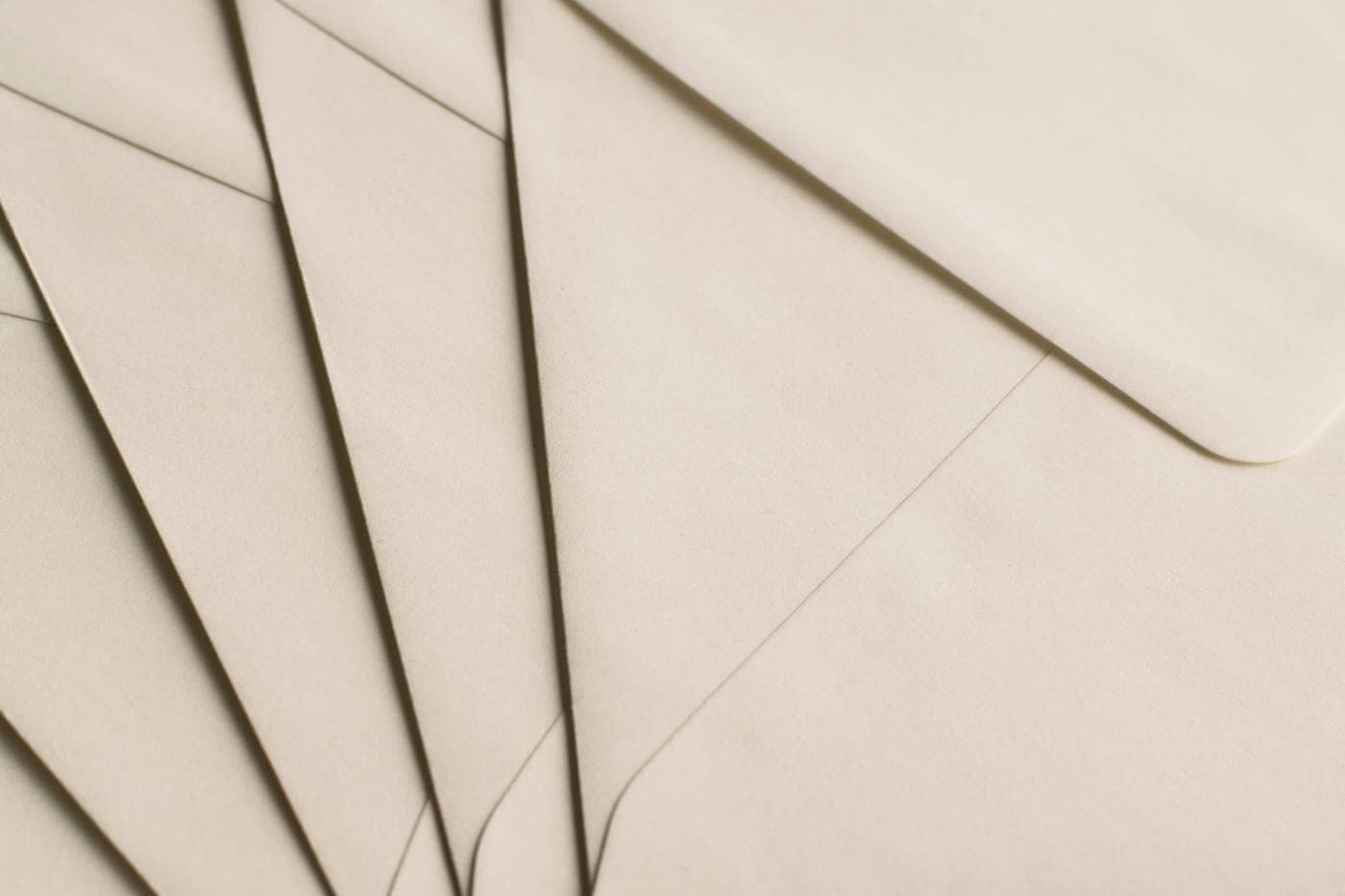 Close-up of cream-colored paper envelopes fanned out in soft warm light