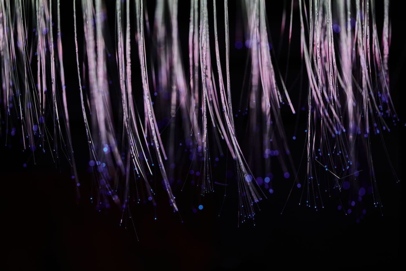 Ethereal white and violet fiber-optic strands cascading with glowing dots on black