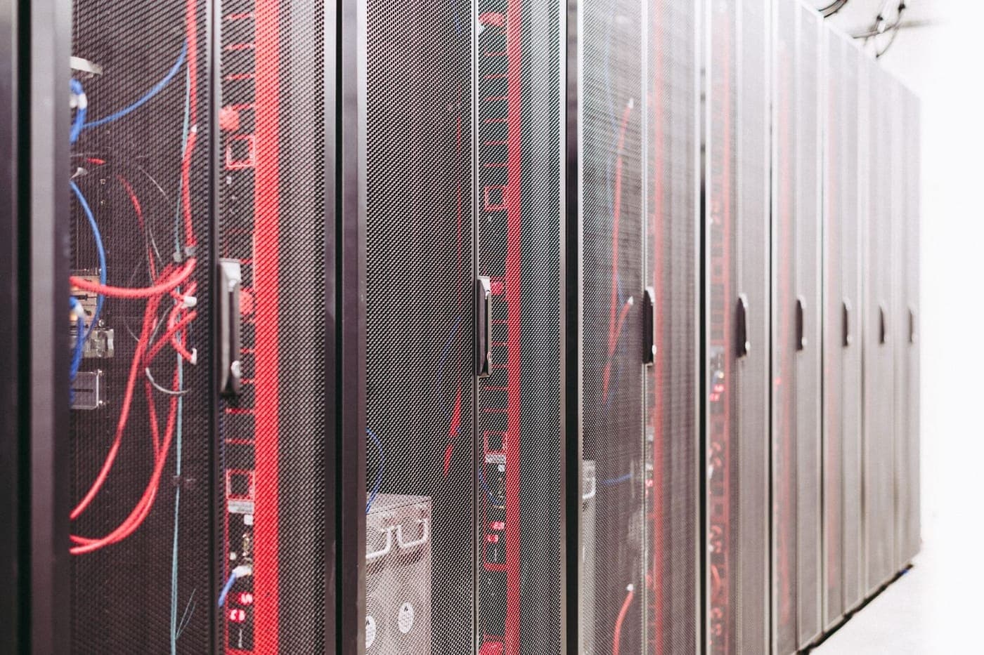 Aisle of black server racks with red and blue cabling in a data center