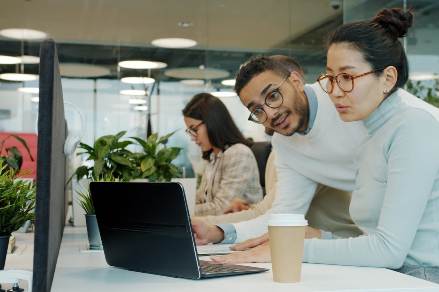 Two colleagues focused on a laptop together in a calm plant-filled office