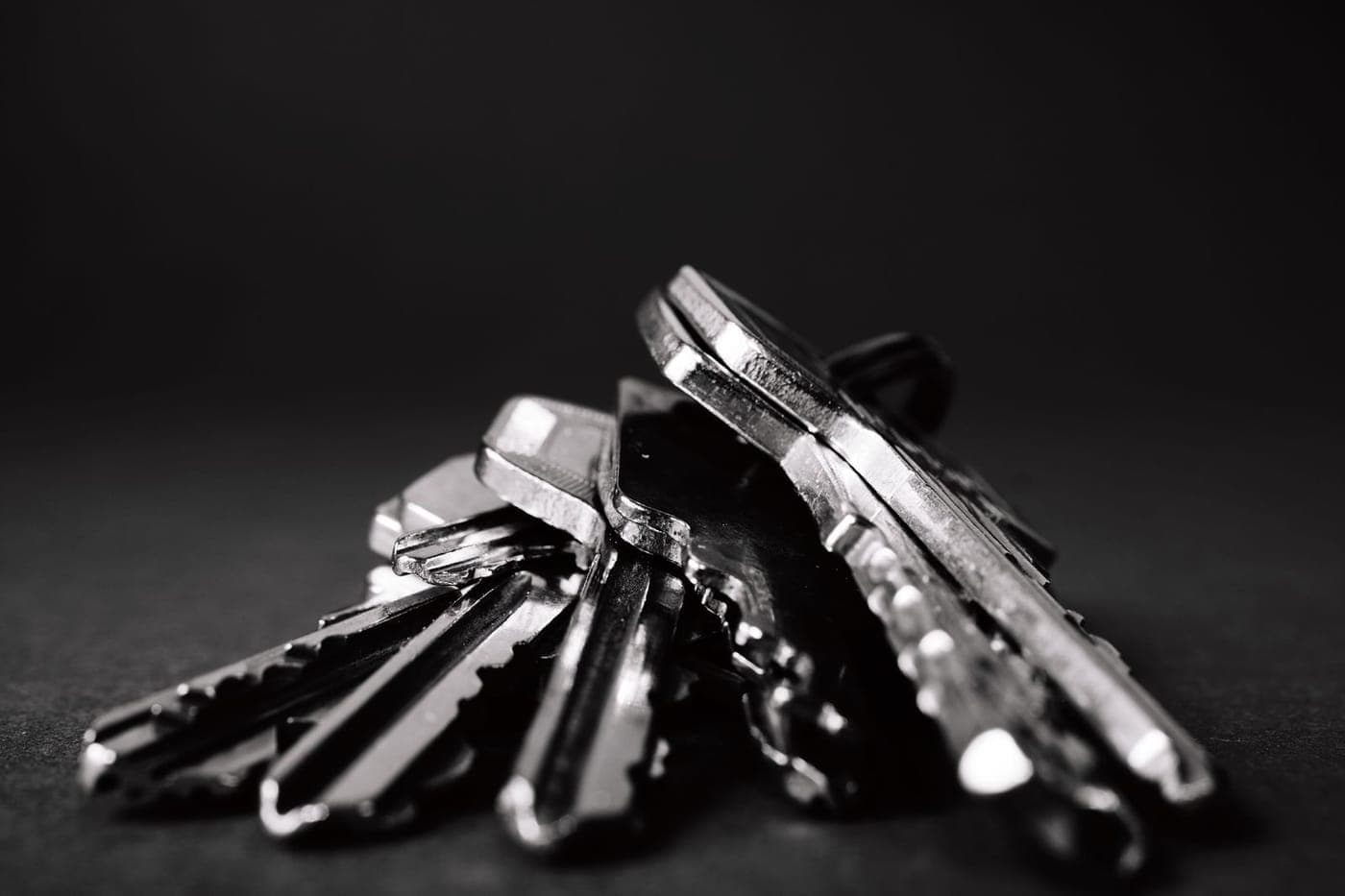 Moody monochrome macro of a small pile of metal keys on a dark surface