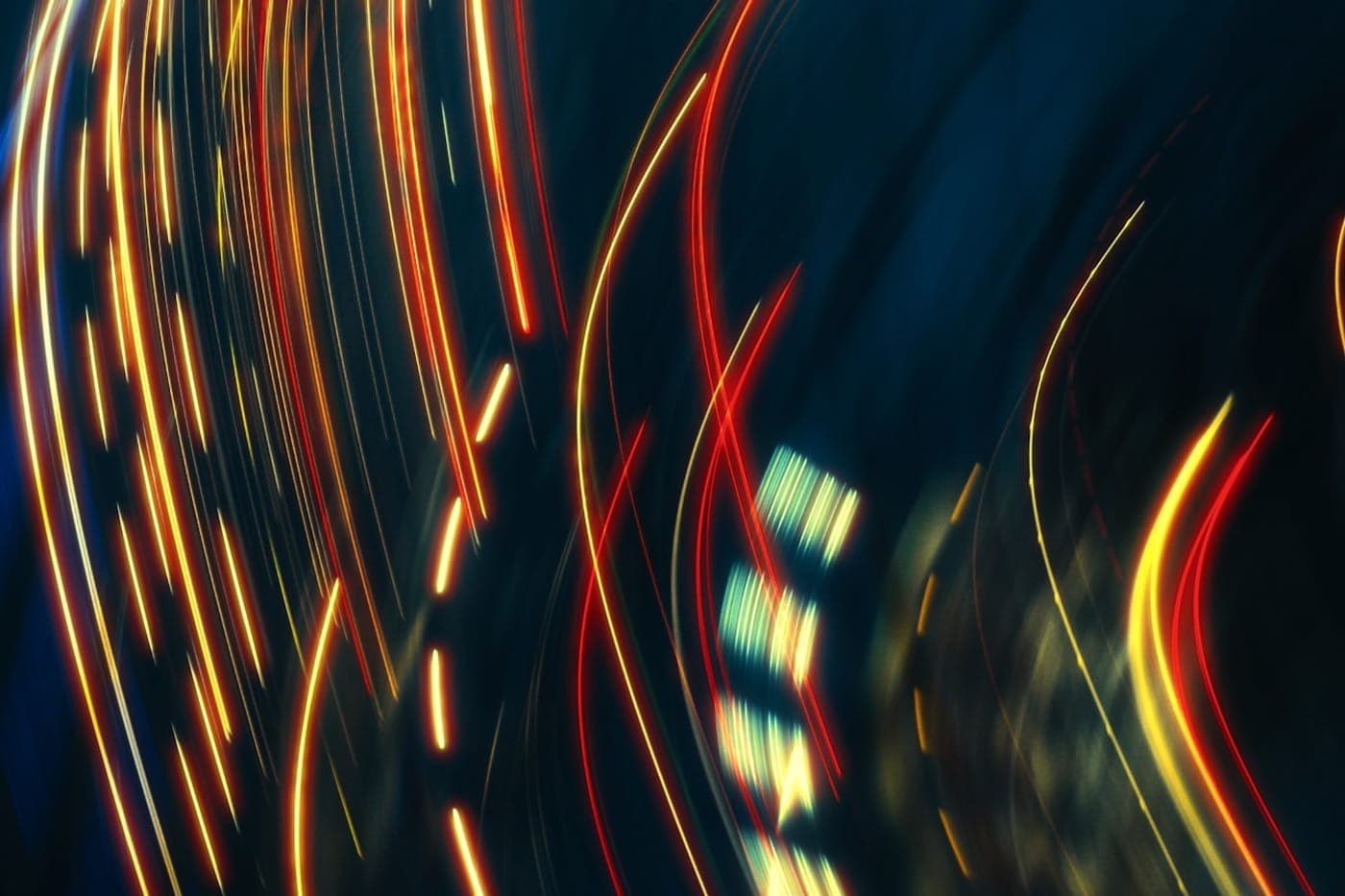Abstract red and gold long-exposure light trails sweeping across a dark blue background