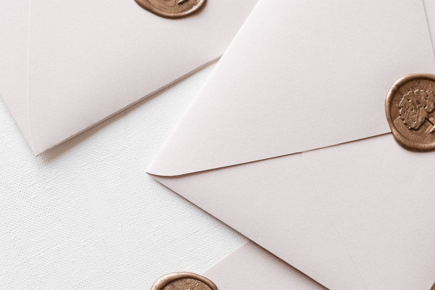White envelopes with bronze wax seals on a pale surface