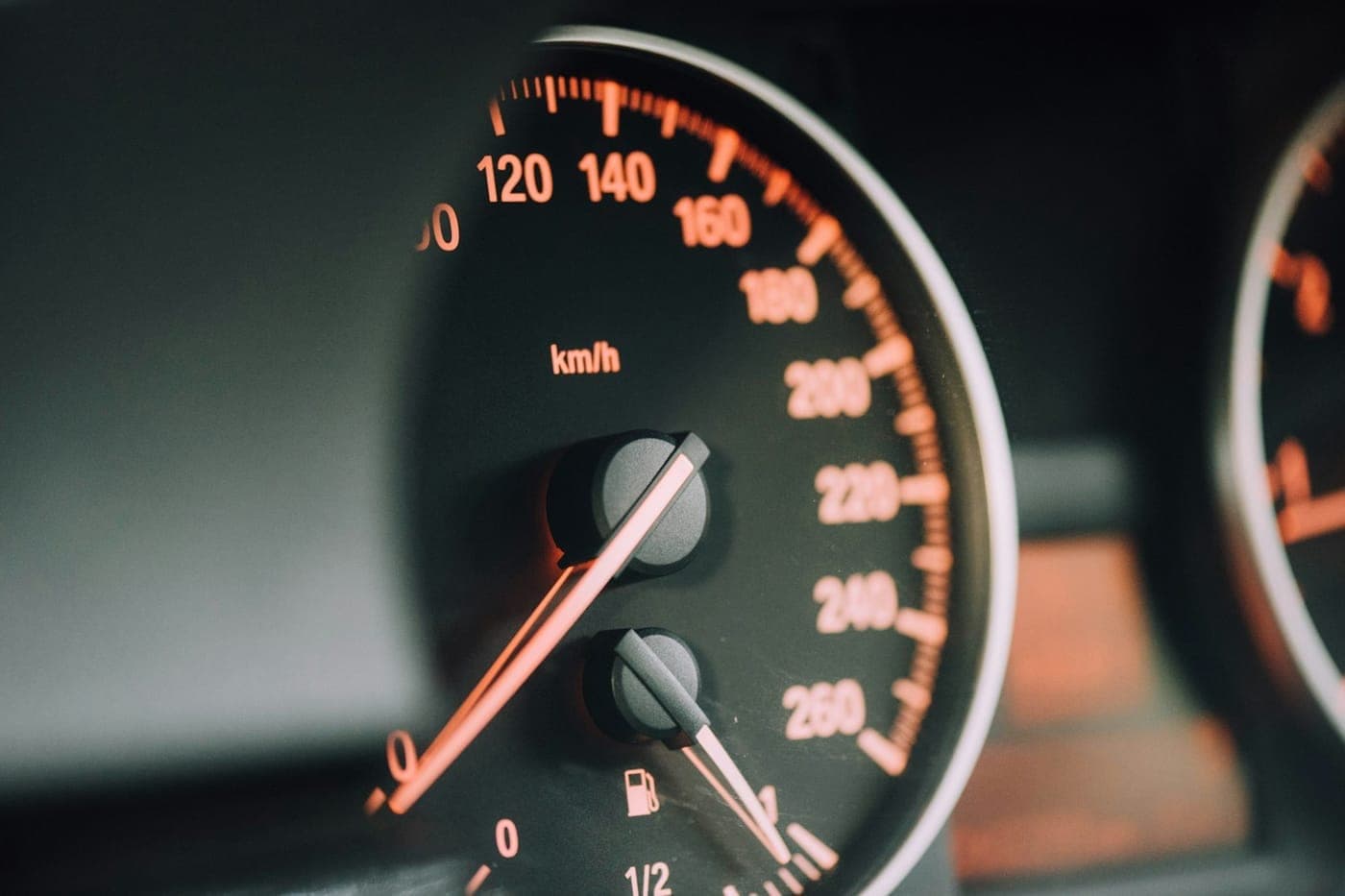 Close-up of a car speedometer with warm amber backlit numbers on a dark dial