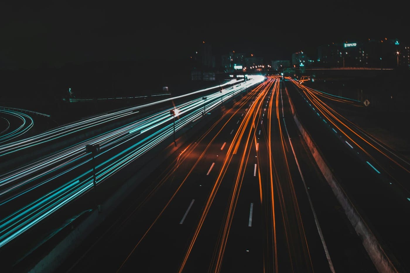 Long-exposure light trails of traffic streaking along a night highway