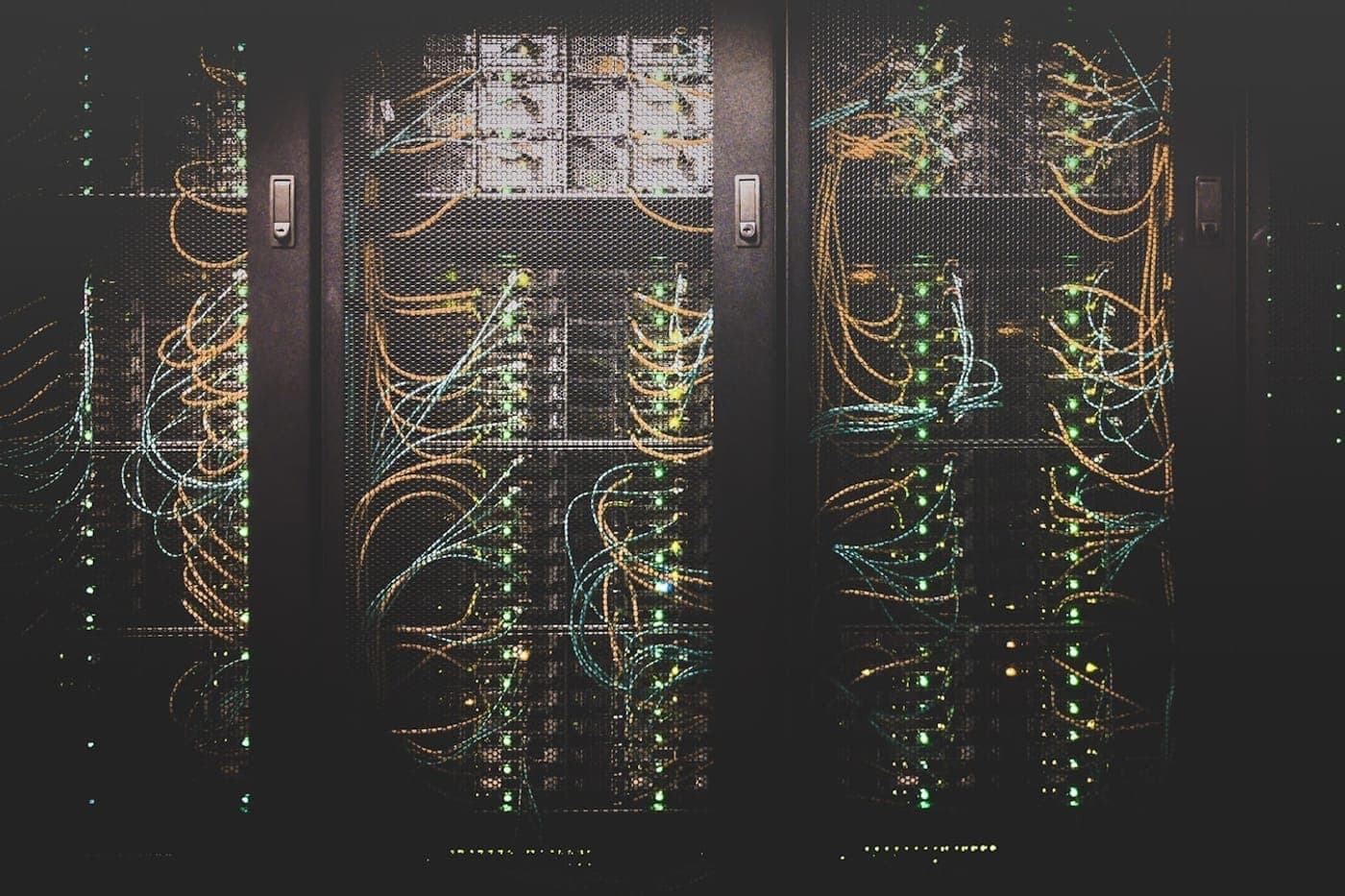 Dark server racks laced with amber and teal network cables and green status LEDs