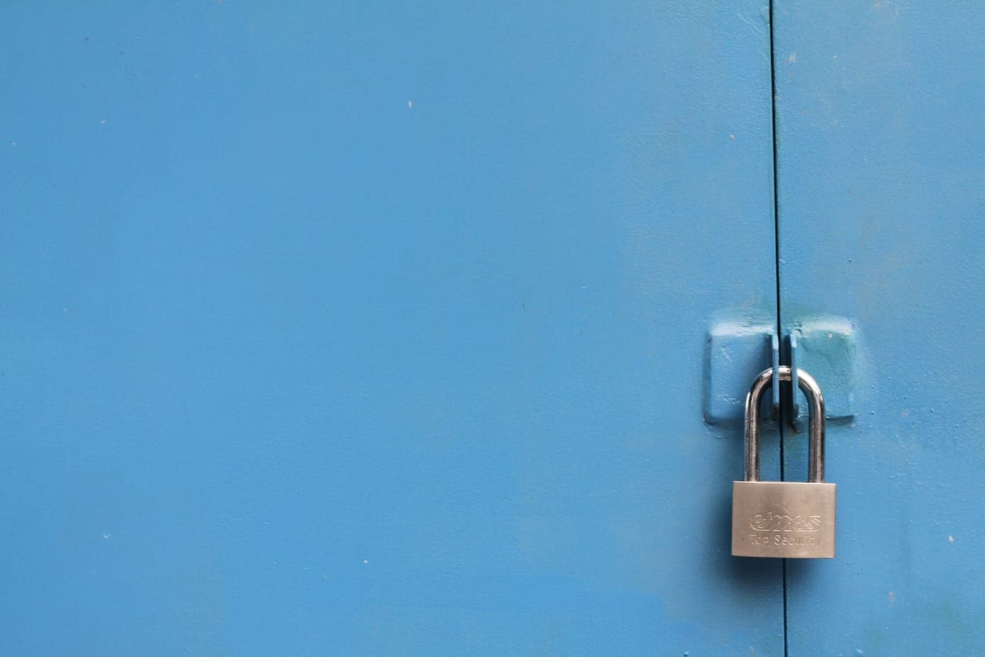 Silver padlock securing a blue metal door