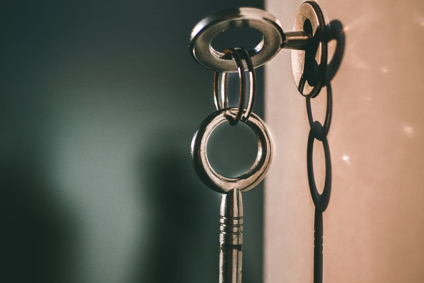 Silver keys hanging in a keyhole against a warm wall