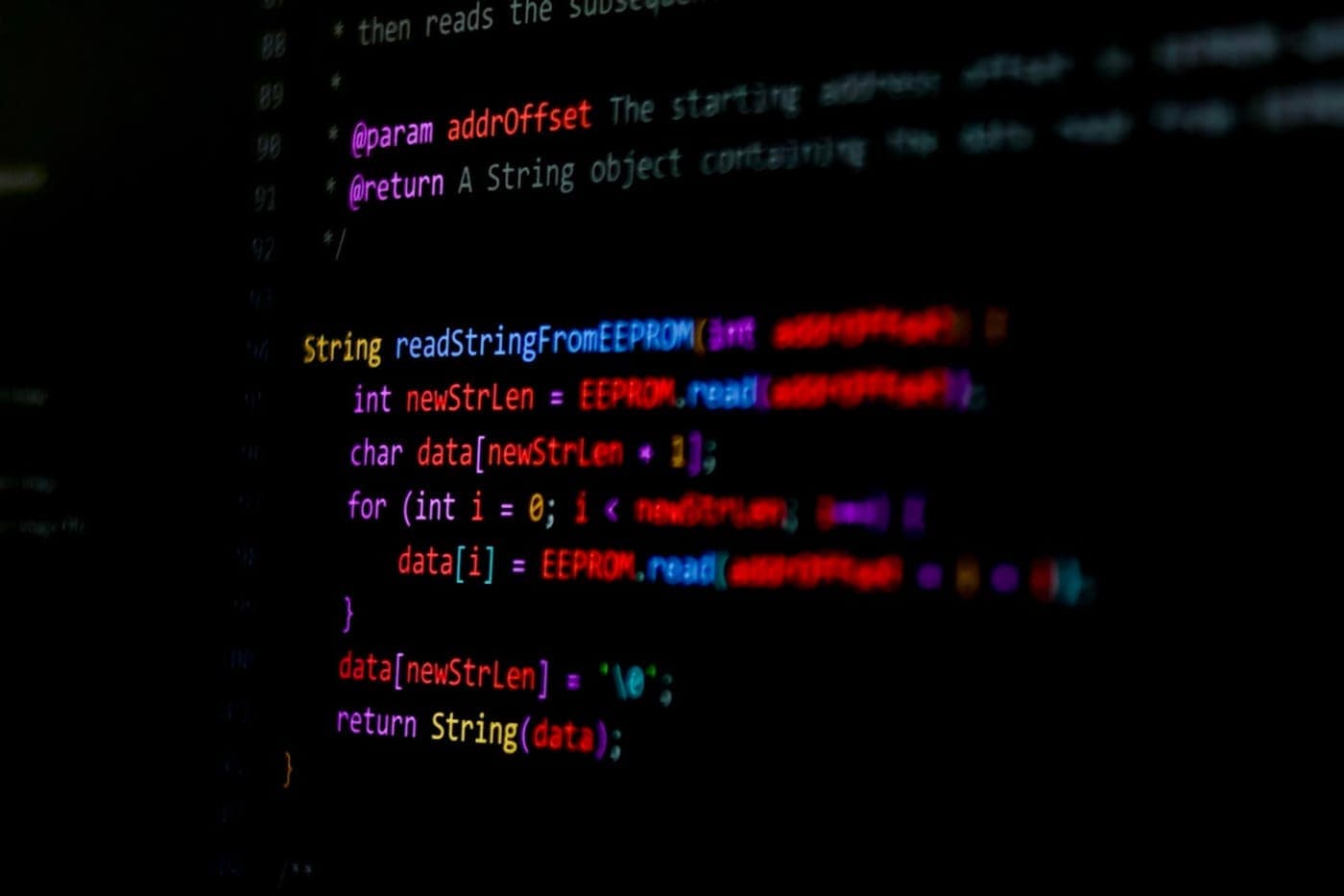 Syntax-highlighted source code displayed on a black screen with shallow depth of field