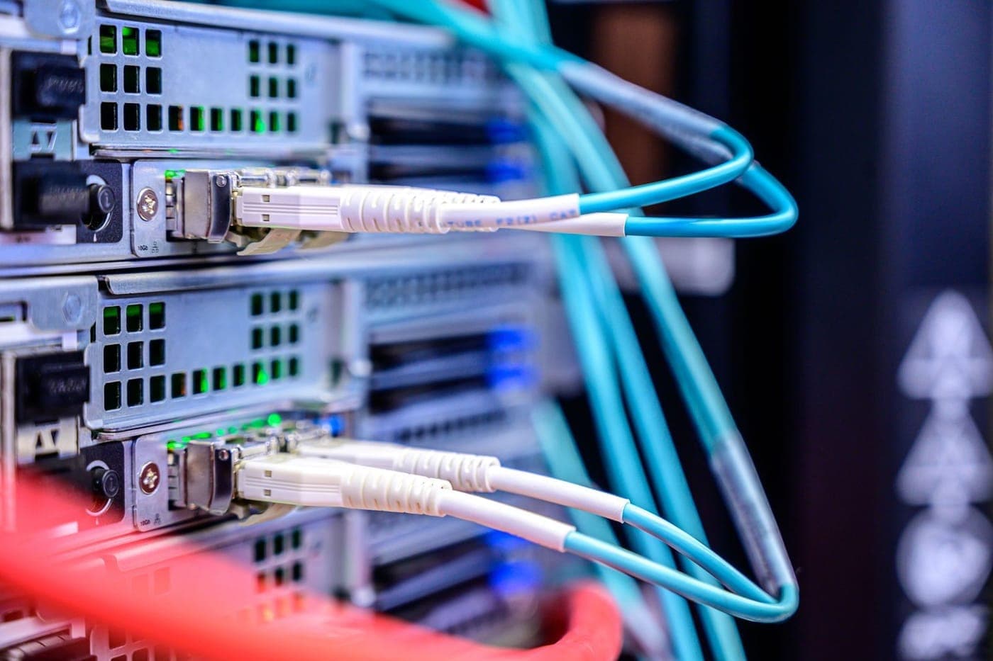 Close-up of teal network cables plugged into server ports with status lights glowing
